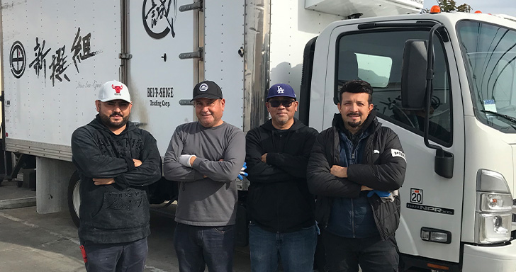 Our truck drivers. White truck with Shin-Sen-Gumi logo and 4 men standing in front of the truck.