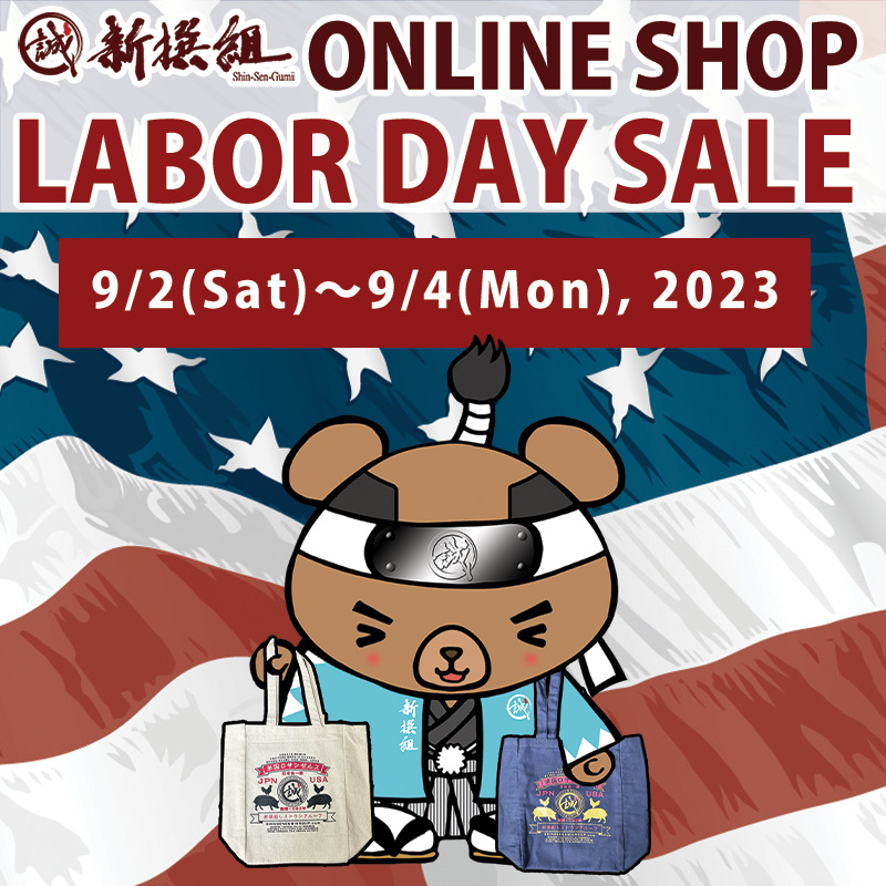 SSG bear holds tote bags with big smile in front of American flag. Shin-Sen-Gumi ONLINE SHOP LABOR DAY SALE / 9/2(Sat)~9/4(Mon), 2023 on the top.